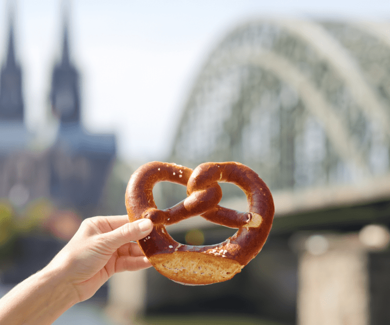 A woman is holding a traditional German pretzel, a must-try dish during the Berlin City break