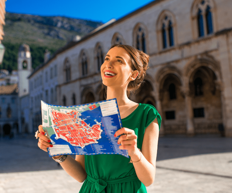 A woman wearing a green dress and holding a map on her City break to Dubrovnik