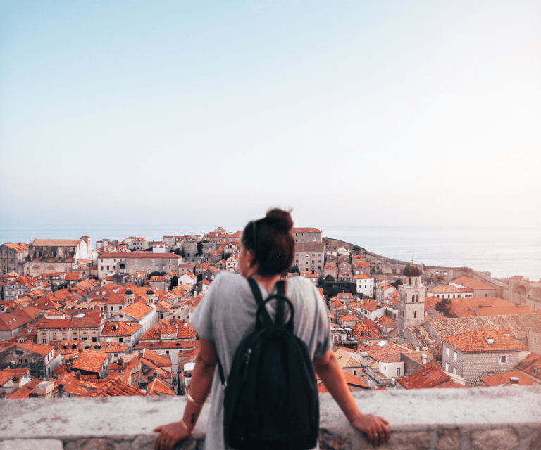 A woman in a grey Tshirt is fcacing away from the camera and admiring the vies on her Dubrovnik weekend getaway