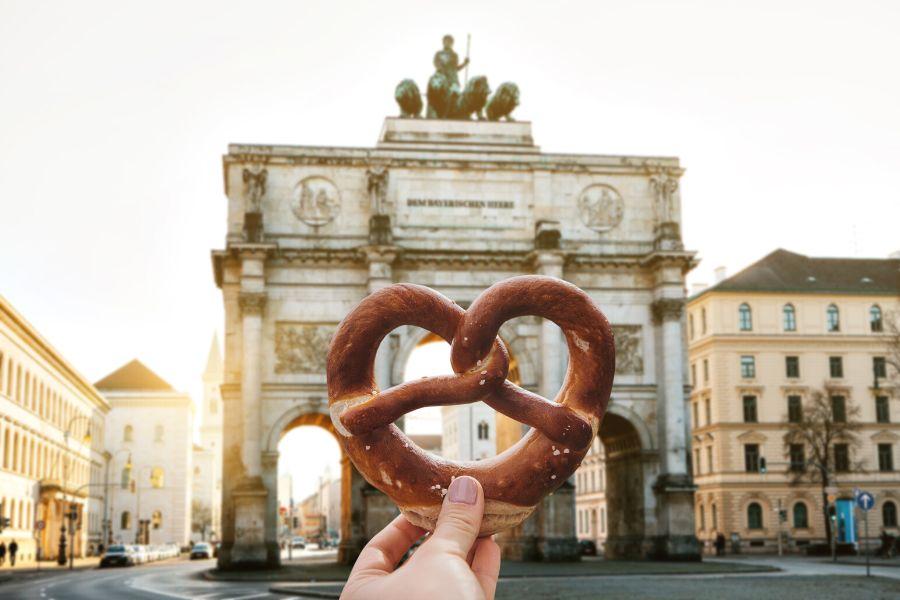 Someone is holding a German krengel in from of the Siegestor, a must-visit sight during a Germany city break