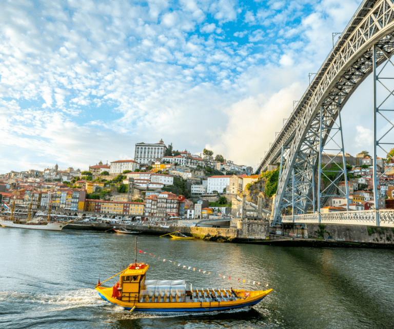 A boat passing under a bridge, one of the iconic symbols of the city and a must-see thing during a Porto getaway