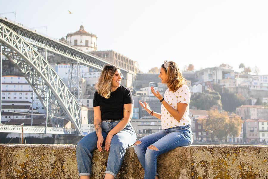 two friends are talking neaк a bridge in Porto during their classic porto city break