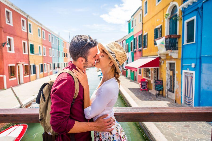 A couple is about to kiss on a bridge in Venice during a romantic getaway