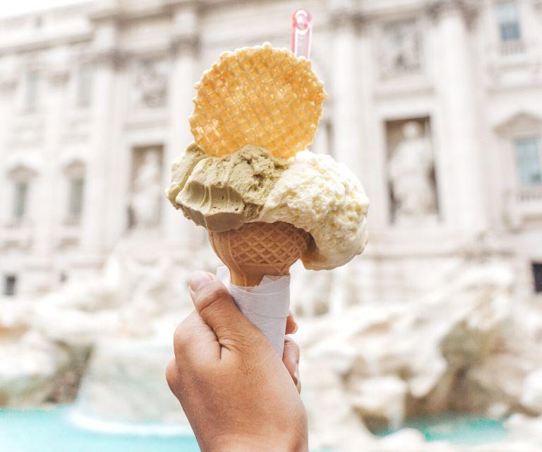 someone is holding traditional Italian gelatto near the Trevi fountain, a must-visit place during a Rome weekend break