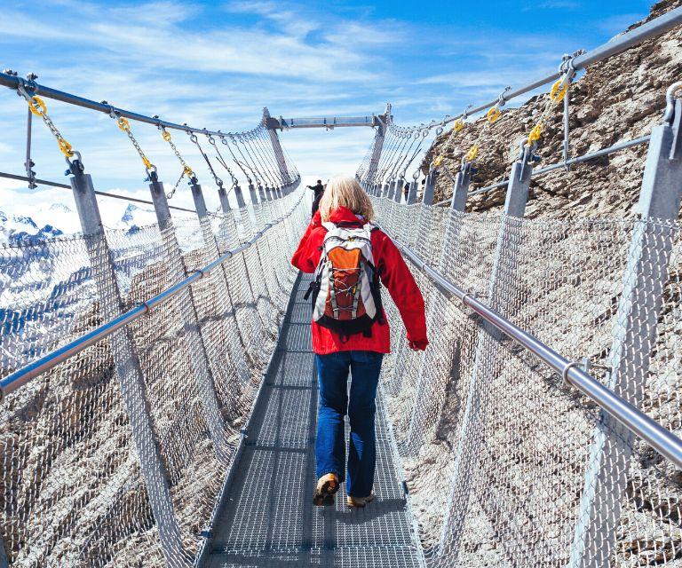 A tourist walking across the mountain Titlis suspension bridge, a must-try experience during a weekend trip to Zurich