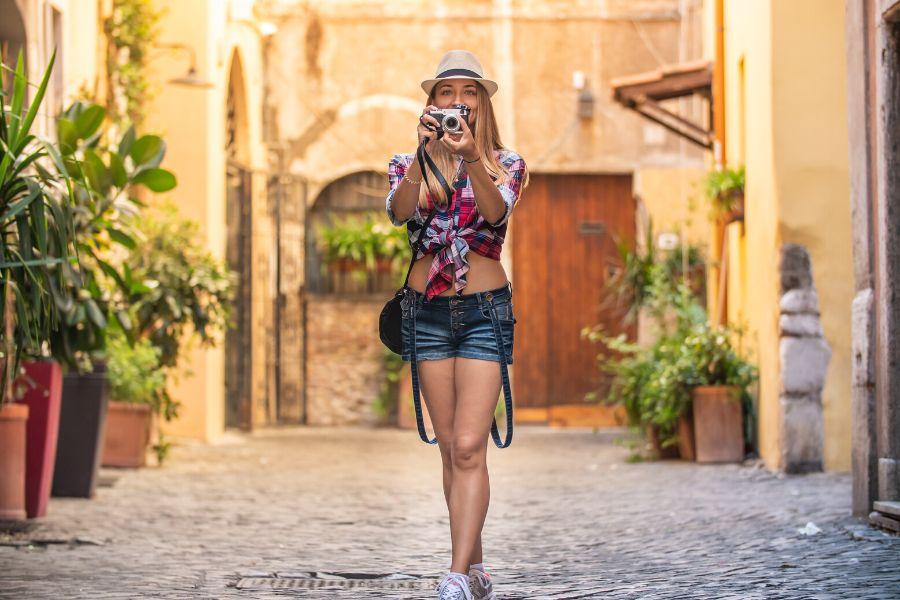 A woman is facing a camera and holding a camera during her off-the-beaten-track tour of Rome