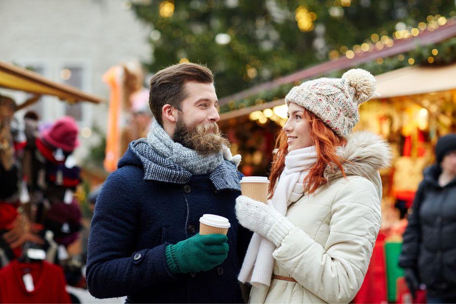 A young couple drinking mulled wine and enjoying each other's company as they explore one of Berlin's Christmas markets