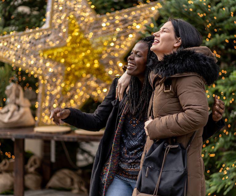 Two people near a Christmas tree and a big golden star made out of golden lights, enjoying their Christmas break to geneva