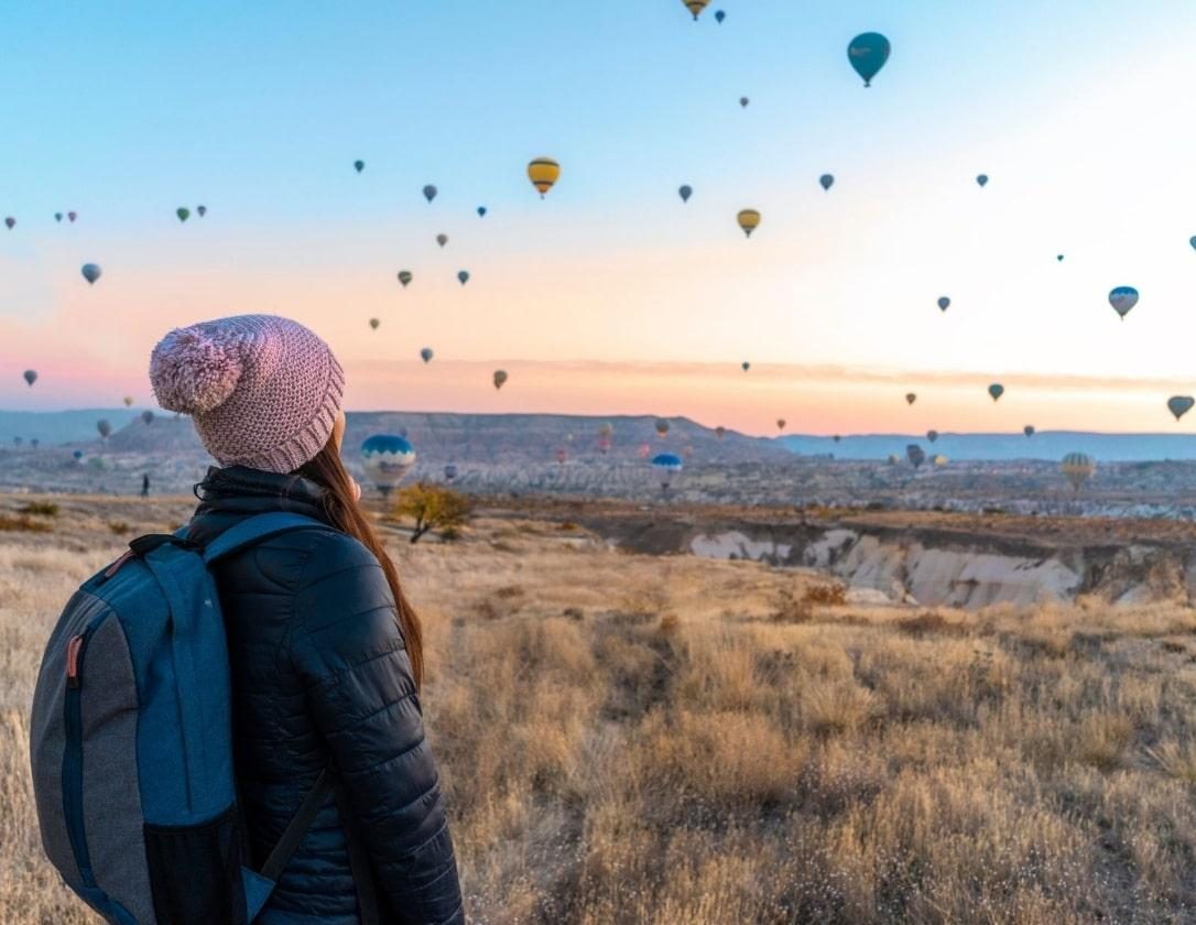 A woman admiring the sky filled with hot air balloons during ger Europe city break