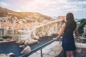 A woman in a navy dress is facing away from the camera and admiring the skyline of Dubrovnik, a fantastic place for a Croatia weekend break