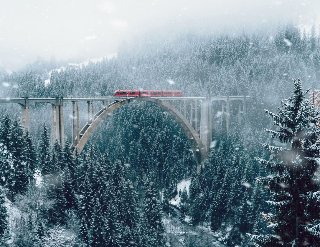A scenic view of a train on a viaduct in winter Switzerland