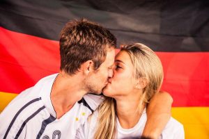 A young couple is kissing with german flag on the background