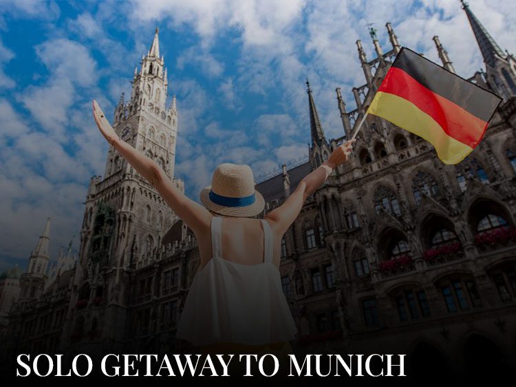 A beaitiful young woman in a lovely hat is holding a german flag and standing at Marienplatz, a must-see place on a Munich city break, and holding a German flag