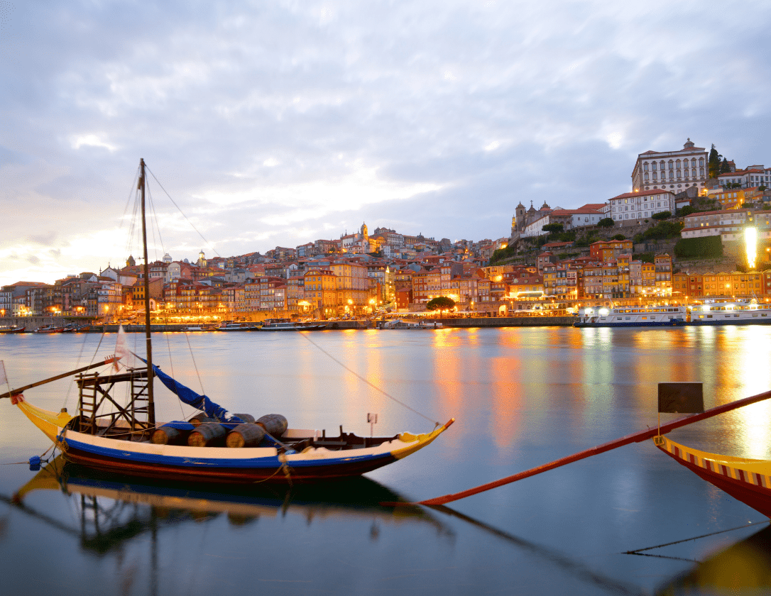 A boat on the Duoro River, the city of Porto is visible in the distance and beautifully lit.