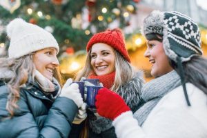Three friends drinking hot mulled wine on a Christmas market in Rome